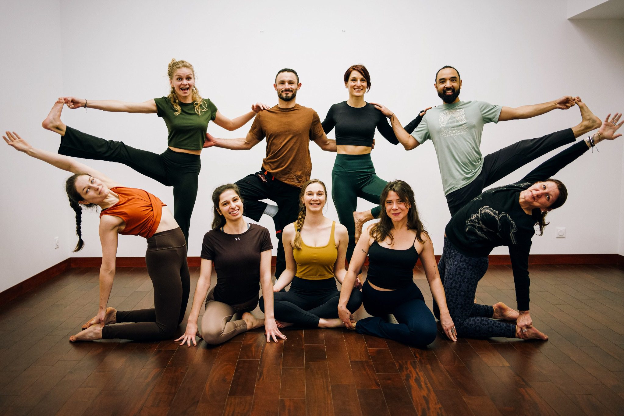 Un groupe souriant en posture de yoga chez Les Yogis